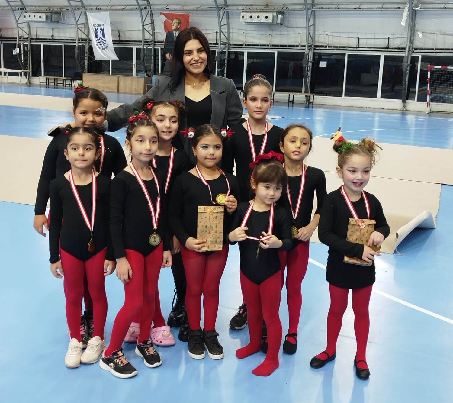 Gösteri sonrası kupalarıyla poz veren minik cimnastikçiler ve antrenörleri