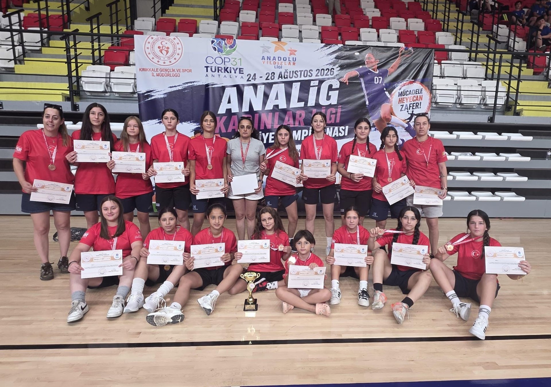ANALİG Hentbol Türkiye Şampiyonası’nda Türkiye üçüncüsü olan Muğla Karması sporcuları ve antrenörleri, başarı belgeleri ve kupayla toplu fotoğrafta